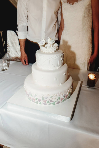 stylische wunderschöne ungewöhnliche weiße Hochzeitstorte mit Geometriekonzept und Vögeln. einzigartig lecker süß - Foto, Bild