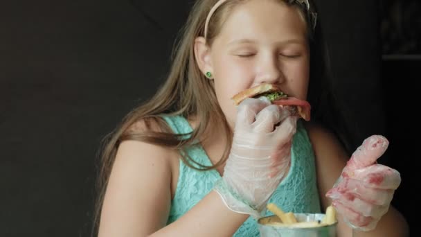 dik meisje gretig eten van een hamburger, concept van een gezond dieet - Video