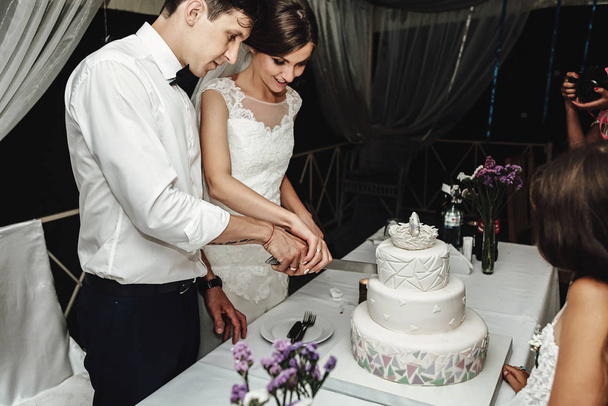 Stylowe wspaniały narzeczeni elegancki cięcia i degustacja niezwykłego biały tort weselny - Zdjęcie, obraz