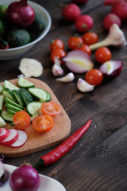 Fresh vegetables sliced for a salad on a cutting board, on an old wooden table - Foto, Imagen