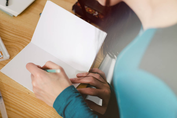 Zbliżenie: kobiecych rąk robiąc notatki w Notatniku w biurze, tonowanie światła - Zdjęcie, obraz