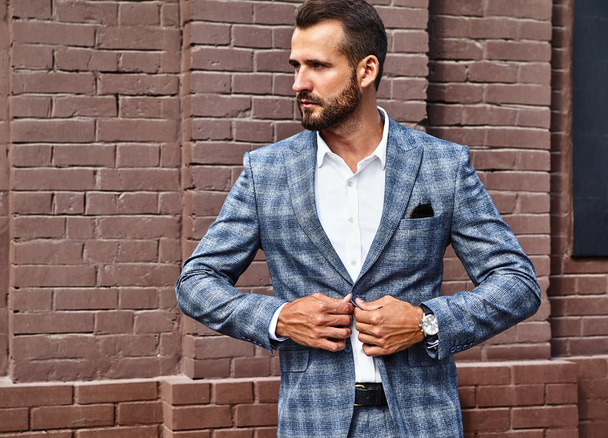 Portrait of sexy handsome fashion businessman model dressed in elegant checkered suit posing on street background. Metrosexual - Zdjęcie, obraz