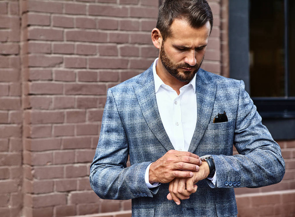 Portrait of sexy handsome fashion businessman model dressed in elegant checkered suit posing on street background. Metrosexual - Φωτογραφία, εικόνα