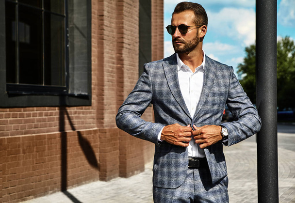 Portrait of sexy handsome fashion businessman model dressed in elegant checkered suit posing on street background. Metrosexual - Fotoğraf, Görsel