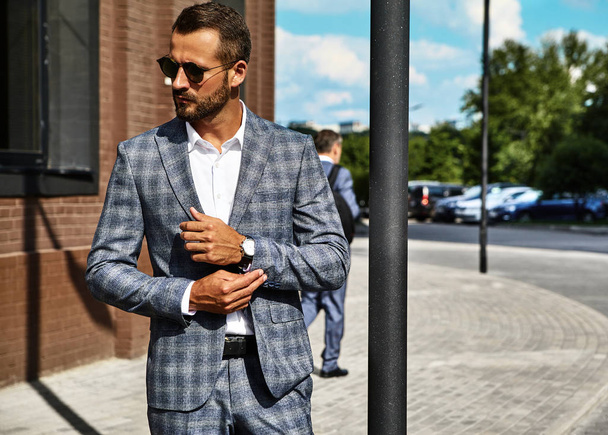 Portrait of sexy handsome fashion businessman model dressed in elegant checkered suit posing on street background. Metrosexual - Fotoğraf, Görsel