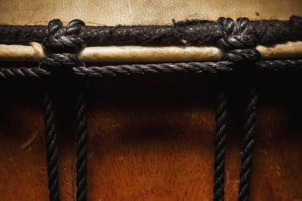 Vista de cerca de un viejo djembe de madera, detalles de cuerdas, piel y madera
.  - Foto, imagen