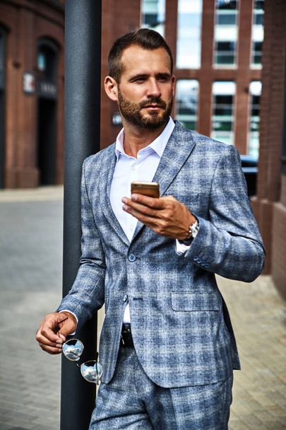 Portrait d'homme d'affaires sexy beau modèle de mode habillé en costume à carreaux élégant ayant conversation mobile d'affaires sur smartphone dans la rue. Metrosexuel
 - Photo, image
