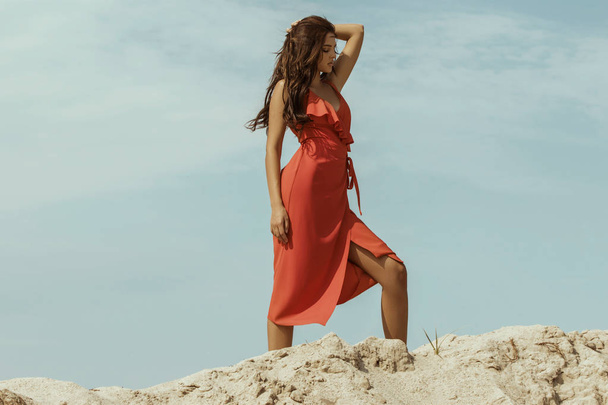 Beautiful female girl model brunette in a dress on the mountain and dessert sand font - Foto, afbeelding