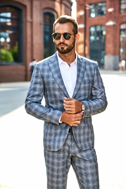 Portrait of sexy handsome fashion businessman model dressed in elegant checkered suit posing on street background. Metrosexual - Photo, image