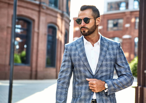 Portrait of sexy handsome fashion businessman model dressed in elegant checkered suit posing on street background. Metrosexual - Photo, Image