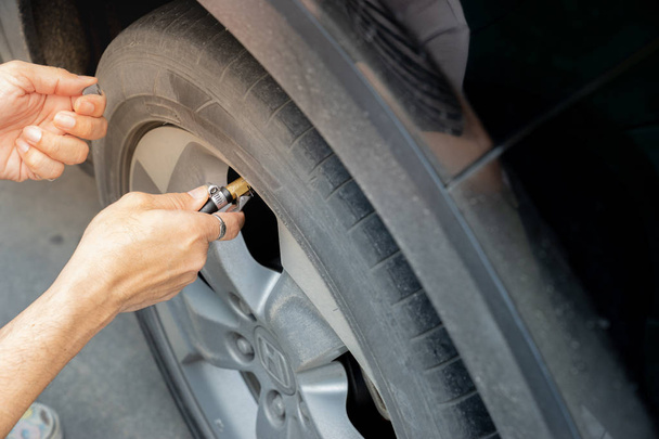 Man filling air in the tires of car. close up hand - Foto, Imagen