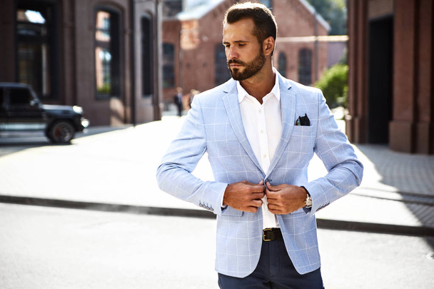 Portrait of sexy handsome fashion businessman model dressed in elegant blue suit posing on street background. Metrosexual - Foto, imagen