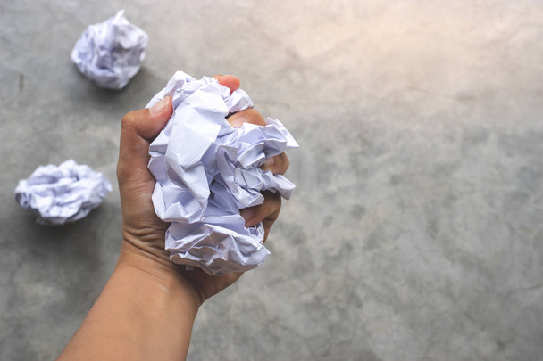 ανθρώπινο χέρι εκμετάλλευση τσαλακωμένο χαρτί μπάλα υπόβαθρο τσιμέντο - Φωτογραφία, εικόνα