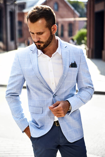Portrait of sexy handsome fashion businessman model dressed in elegant blue suit posing on street background. Metrosexual - 写真・画像