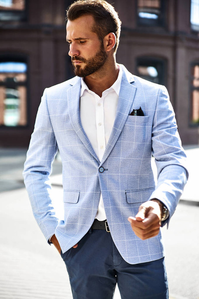 Portrait of sexy handsome fashion businessman model dressed in elegant blue suit posing on street background. Metrosexual - Zdjęcie, obraz
