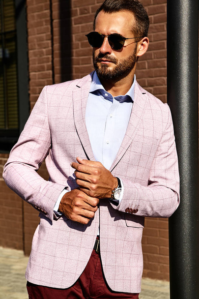 Portrait of sexy handsome fashion businessman model dressed in elegant suit posing near brick wall on the street background. Metrosexual - Zdjęcie, obraz