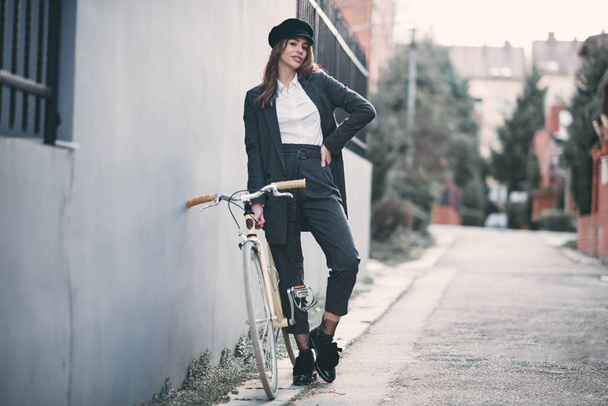 Γυναίκα να στέκεται στο δρόμο nexzt το ποδήλατο της fixie. - Φωτογραφία, εικόνα