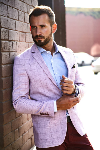 Portrait of sexy handsome fashion businessman model dressed in elegant suit posing near brick wall on the street background. Metrosexual - 写真・画像