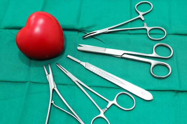 Strumenti chirurgici e cuore di gomma sul tessuto verde medico
 - Foto, immagini