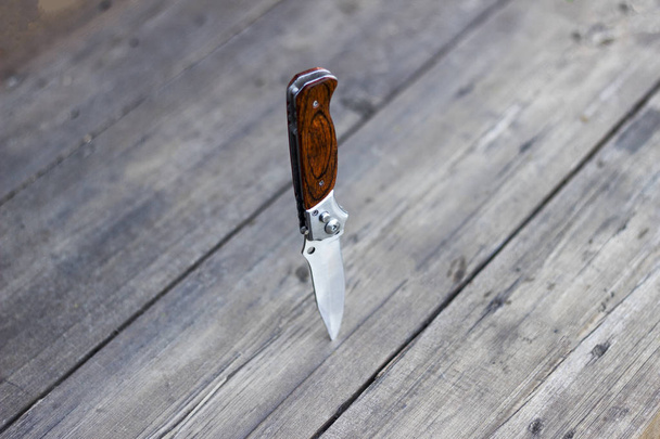 Folding knife stands in a wooden table, close-up - Photo, Image