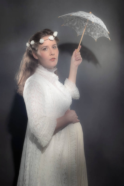 Historical pregnant brunette woman in white dress holding umbrella. - Photo, Image