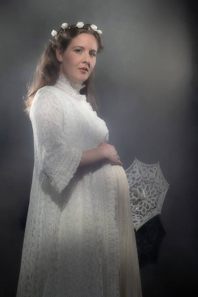 Histórica mujer morena embarazada en vestido blanco con paraguas
. - Foto, imagen