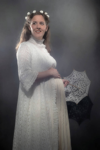 Historical pregnant brunette woman in white dress holding umbrella. - Photo, Image
