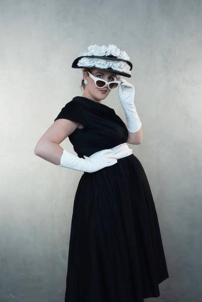 Vintage 1950s pregnant woman in white sunglasses and black dress. - 写真・画像