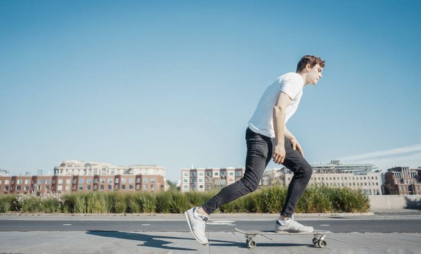 Young attractive man riding longboard in the park. - Photo, Image