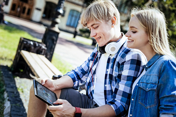Friendly college students smiling and using touchpad outdoors - Foto, imagen