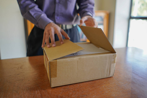 Selective focus of young man unboxing a parcel - Фото, изображение