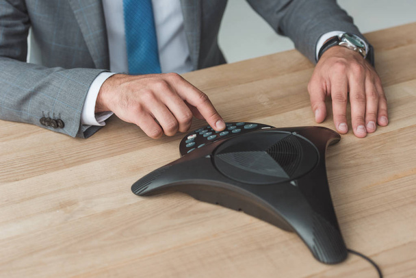 cropped shot of businessman pushing button of speakerphone at workplace - Photo, image