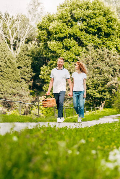 heureux jeune couple avec panier pique-nique marche dans beau parc
 - Photo, image