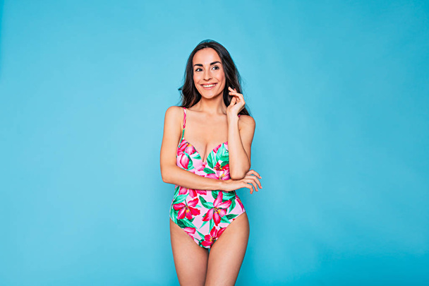 Young woman in stylish swimsuit posing on blue background - Fotoğraf, Görsel
