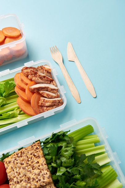 Nahaufnahme der Anordnung von Besteck und Lebensmittelbehältern mit frischem, gesundem Gemüse und Fleischhintergrund - Foto, Bild