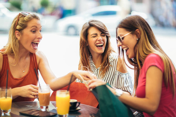 Tres mujeres jóvenes bebiendo jugo en la cafetería después de una compra
 - Foto, imagen