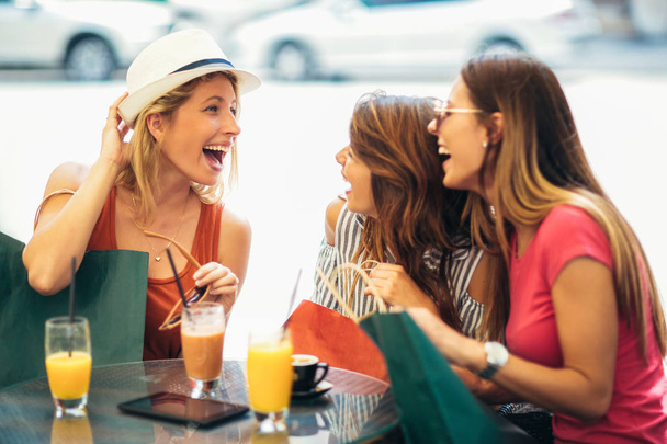 Trois jeunes femmes buvant du jus dans un café après un shopping
 - Photo, image