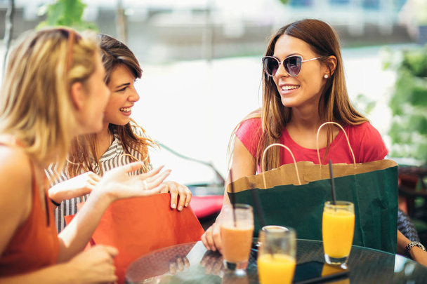 Tres mujeres jóvenes con bolsas de colores en la cafetería después de comprar
 - Foto, imagen