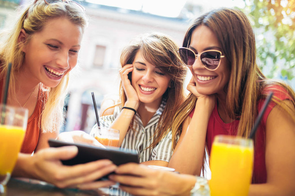 Amigos femeninos usando tableta PC y divertirse en la cafetería
  - Foto, imagen