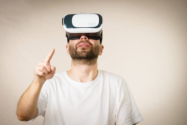 Adult short bearded guy exploring virtual reality wearing VR goggles being into technology. - 写真・画像