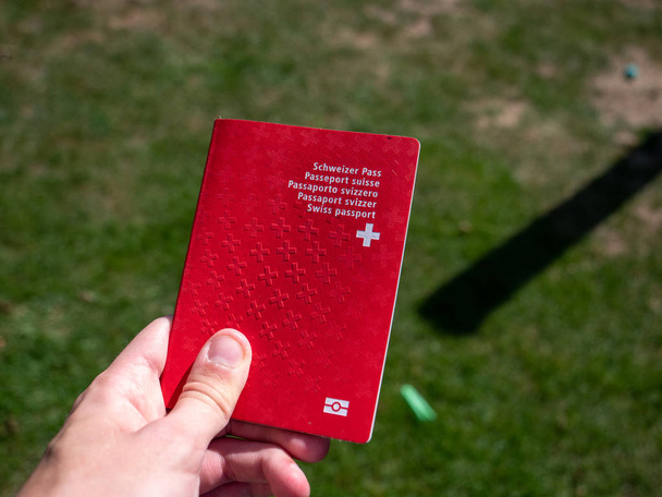 person holding the swiss passport on a sunny day grass background - Photo, Image