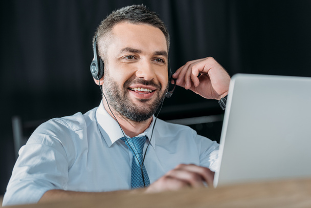 sorrindo suporte hotline trabalhador com laptop e microfone no trabalho
 - Foto, Imagem