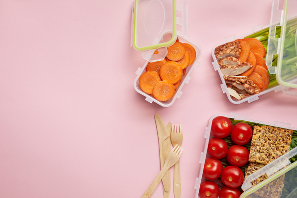 επίπεδη lay με υγιεινό φαγητό διατεταγμένα σε δοχεία τροφίμων και τα μαχαιροπήρουνα που απομονώνονται σε ροζ - Φωτογραφία, εικόνα