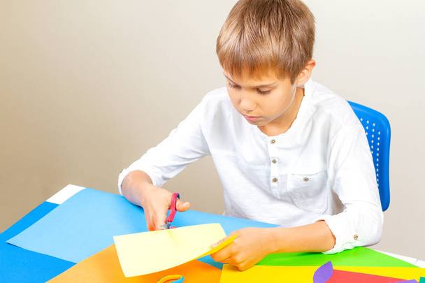 Lapsen leikkaus värillinen paperi sakset pöydässä
 - Valokuva, kuva
