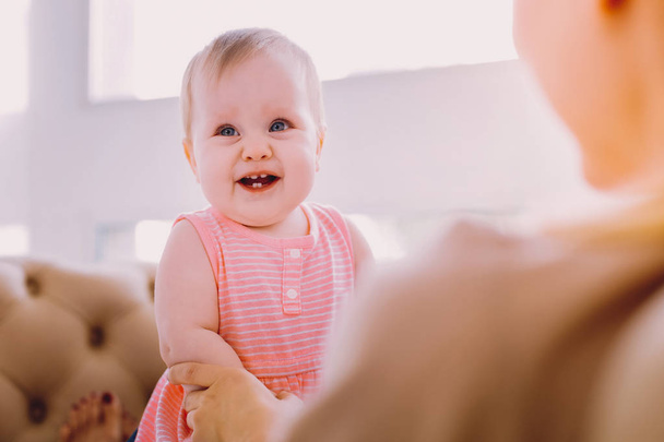 Bebé positivo sonriendo mientras está sentado en las rodillas de una madre
 - Foto, imagen