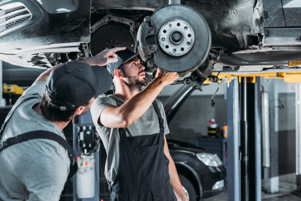 auto mechanics repairing car without wheel in workshop - Photo, Image