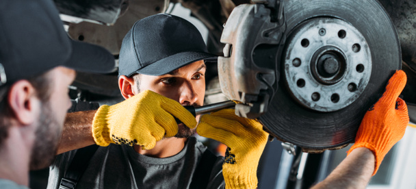 Mechaniker reparieren Auto ohne Rad in Werkstatt - Foto, Bild