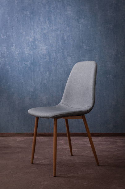La silla gris textil moderna con la madera sobre el fondo de la pared. Buen concepto para el hotel
. - Foto, Imagen