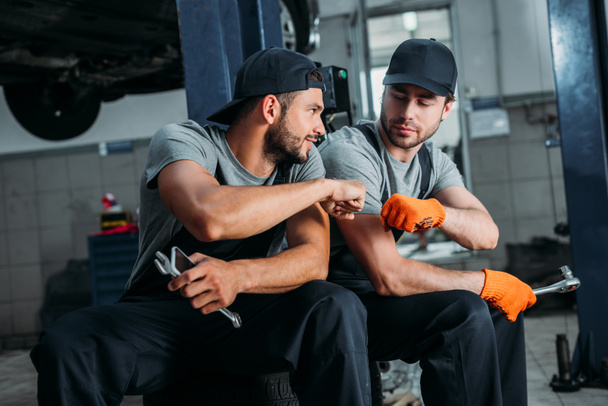 Handwerker stoßen in Mechanikerwerkstatt mit Fäusten zusammen - Foto, Bild