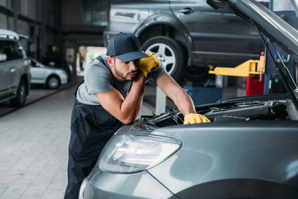 workman in uniform repairing car in mechanic shop - Foto, Bild
